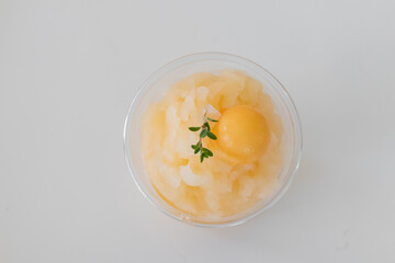 A refreshing dessert featuring sorbet topped with a vibrant yellow scoop and a sprig of herbs, perfect for summer treats.