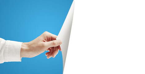 A hand holding and turning a blank white sheet of paper, with a blue background on the left side...