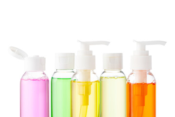 Various bottles with colored liquids and pumps arranged on white background