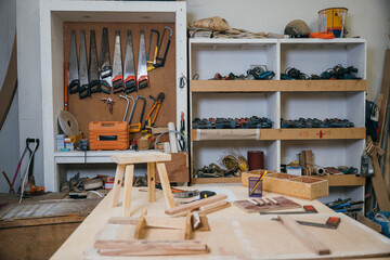 Vintage wooden workbench in a cluttered workshop with various tools and equipment. Old tools hang on the wall, ideal for product display, carpentry, woodwork, and craftsmanship workbench concepts