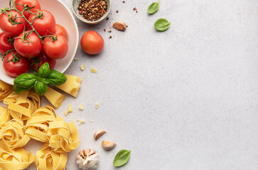 Italian pasta, tomatoes, garlic, cheese, basil and spices creating a culinary frame on a textured background