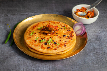 Aloo paratha, a popular North Indian dish, especially in Punjab, is a stuffed flatbread filled with spiced mashed potatoes. It's traditionally served hot with tangy achar (pickle), refreshing chutney,