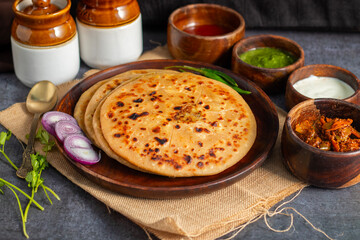 Aloo paratha, a popular North Indian dish, especially in Punjab, is a stuffed flatbread filled with spiced mashed potatoes. It's traditionally served hot with tangy achar (pickle), refreshing chutney,