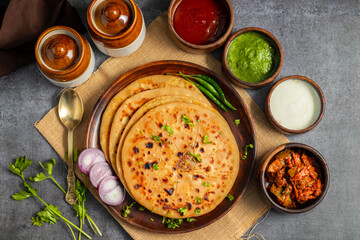 Aloo paratha, a popular North Indian dish from Punjab, Uttar Pradesh, and Bihar, is a stuffed flatbread filled with spiced potatoes, served hot with butter and tangy pickle.