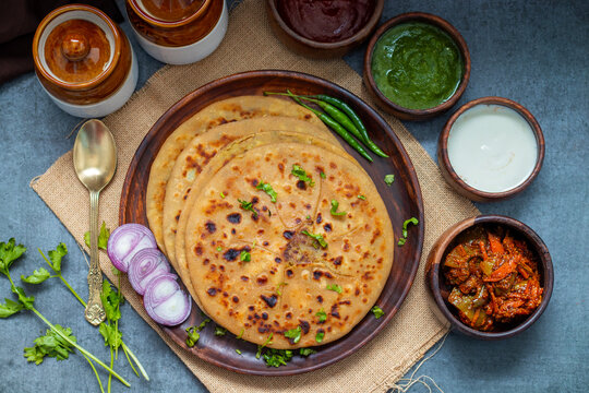 Aloo paratha, a North Indian favorite from Punjab, Uttar Pradesh, and Bihar, is a stuffed flatbread with spiced potato filling, served hot with tangy achar and chutney.