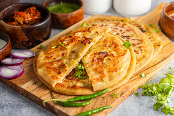 Aloo paratha, a popular North Indian dish, especially in Punjab, is a stuffed flatbread filled with spiced mashed potatoes. It's traditionally served hot with tangy achar (pickle), refreshing chutney,