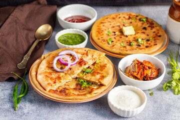 Aloo paratha, a North Indian favorite from Punjab, Uttar Pradesh, and Bihar, is a stuffed flatbread with spiced potato filling, served hot with tangy achar and chutney.