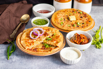 Aloo paratha, a popular North Indian dish, especially in Punjab, is a stuffed flatbread filled with spiced mashed potatoes. It's traditionally served hot with tangy achar (pickle), refreshing chutney,