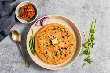Aloo paratha, a flavorful Indian flatbread stuffed with spiced mashed potatoes, served hot with tangy pickle (achar) and refreshing chutney, creating a perfect balance of zest and warmth.