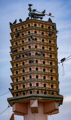 Fototapeta premium Tall pigeon tower filled with birds, standing stark against a cloudy sky backdrop