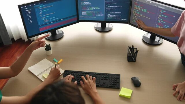 Slow motion back end software developer engineer for computer programming working together on debugging writing computing code, solving complex algorithms display on monitor in office. Burgeoning