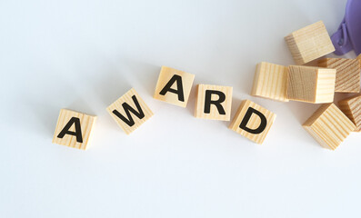 The text of the AWARD on wooden cubes on a light background, a table with a stack of books and wooden cubes.