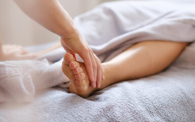 Reflexologist applying pressure to foot with thumbs