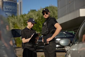 Patrol police team working on city street with parked cars