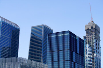Modern Skyscrapers Under Clear Blue Sky with Construction Activity Highlighting Urban Development and Architectural Innovation in a Metropolitan Landscape
