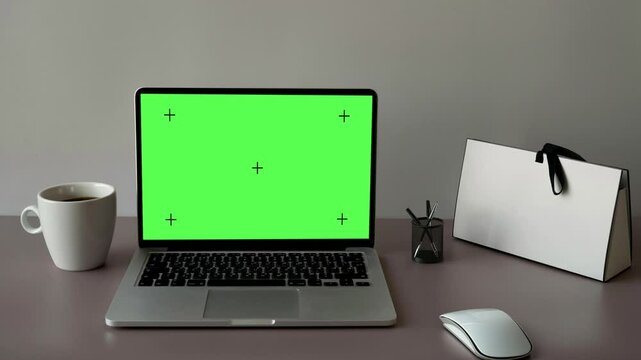 Laptop Computer Monitor Standing on a Desk with a Green Screen Chroma key Mockup Display. Green Screen Display with Isolated Placeholder with Tracker Marker.