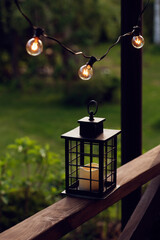 evening summer garden, wooden porch decorated with light bulbs and candle light