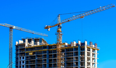 Two construction cranes are building a house