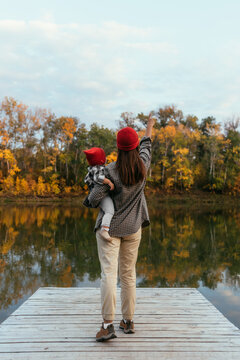 A woman with a child travels through picturesque places. Family on the background of a forest lake, rear view. People on the background of the autumn landscape, rear view. Mom and child are traveling