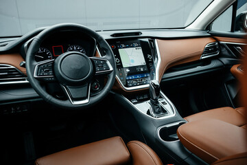 Modern brown car interior, leather steering wheel, climate control, large navigation screen, air...
