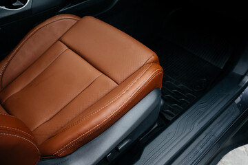 Modern brown car interior, leather steering wheel, climate control, large navigation screen, air ducts, deflectors on the car panel. Interior details.