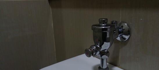 Close up urinal water dispenser, pushing button of flushing toilet.