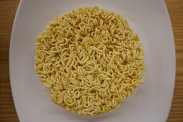 Instant noodles in a white plate on a wooden table