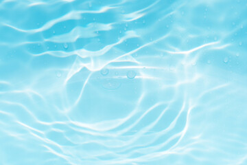 Blue water with ripples on the surface. Defocus blurred transparent blue colored clear calm water surface texture with splashes and bubbles. Water waves with shining pattern texture background.