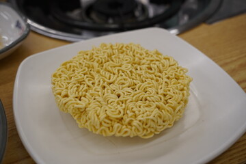 Instant noodles in a white plate on a wooden table