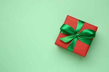 Beautiful gift box tied with bow on color background 