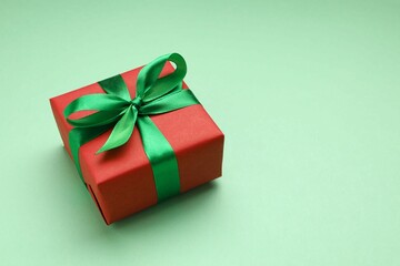 Beautiful gift box tied with bow on color background 