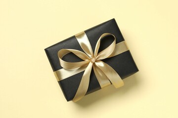 Beautiful gift box tied with golden bow on color background 