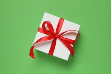 Beautiful gift box tied with bow on color background 