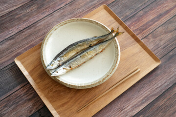 Grilled saury, most important autumn food for Japanese people, is served on simple plate on tray on...