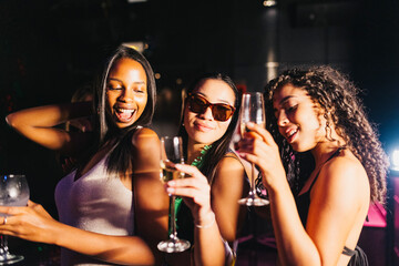 Group of joyful friends dancing at a lively party in a night club. Young smiling women dancing and having fun in a night out.