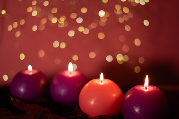  Four glowing Advent candles, symbolizing love, peace, joy, and hope, set against a red background with soft bokeh lights creating a serene and festive atmosphere