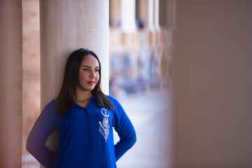 Portrait of a Moroccan woman, young, beautiful, dark-haired, with a blue abaya, standing, with a...