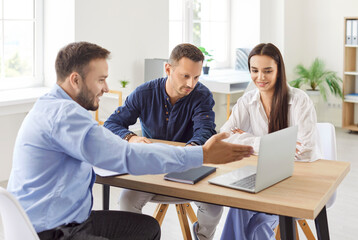 Couple of clients are engaged in conversation with a consultant or agent during an office briefing,...