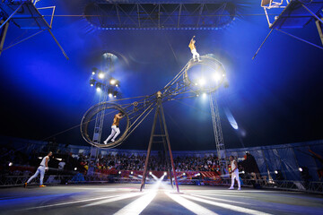 Brave male acrobats in the rotating wheel of death perform under the dome of the circus. © Studio Peace