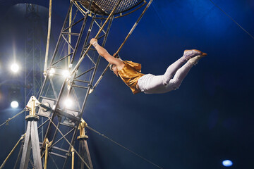 Brave male acrobats in the rotating wheel of death perform under the dome of the circus.