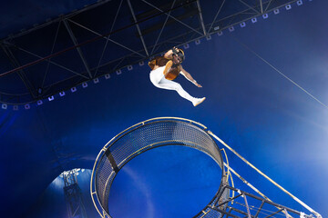 Brave male acrobats in the rotating wheel of death perform under the dome of the circus.