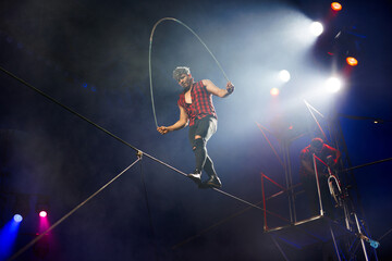 Circus performance of aerial acrobats-tightrope walkers. Tightrope walker jumps on a rope on a rope. © Studio Peace