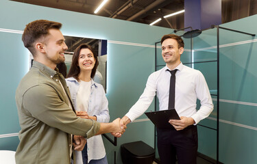 A smiling salesman in a plumbing store shakes hands with a customer, close-up. A young couple is happy with their purchase. A man shakes hands with a salesman. Consultation at a plumbing store