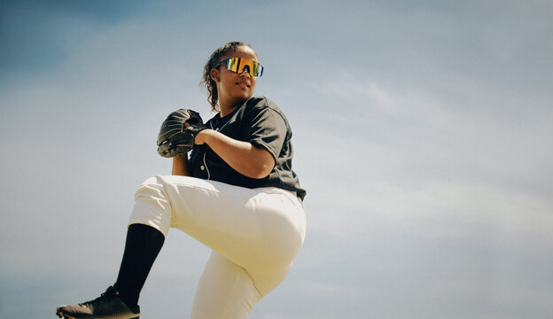 Female professional baseball athlete in mid-pitch showcasing skill and determination