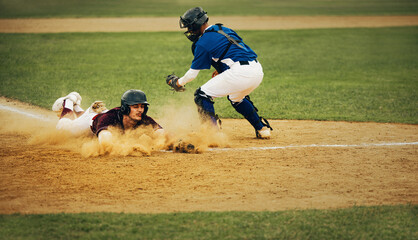 Intense baseball action as player slides home with dust cloud while catcher prepares for tag