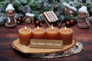Dekoration zum vierten Advent: Adventskranz mit vier braunen Kerzen, kleinen Püppchen,  Weihnachtsschmuck und der Beschriftung einen schönen vierten Advent.