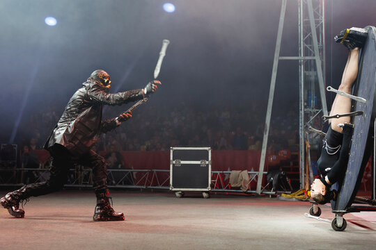 A circus show with knife throwing in the circus arena. The man in the mask dreams of knives.