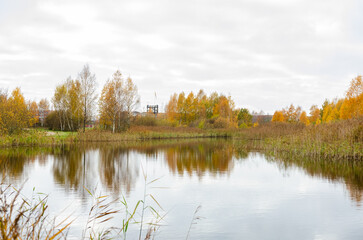 Calm autumn reflections on a serene forest lake. Still water reflecting trees, peaceful autumn atmosphere, wide-angle shot, taken from ground level, rural location, seasonal landscape.