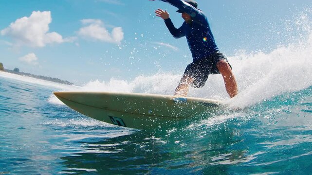 Adult male surfer rides the wave and makes perfect sharp turn with spray. Tropical surfing in the Maldives