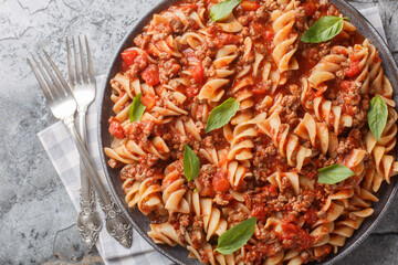 Italian Fusilloni Pasta with ground meat, tomato sauce and vegetables closeup on the plate on the table. Horizontal top view from above